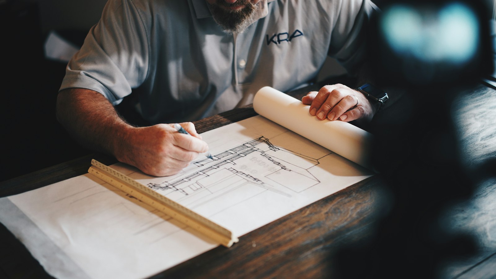 Plano de una vivienda sobre la mesa, mientras se revisa el dibujo.